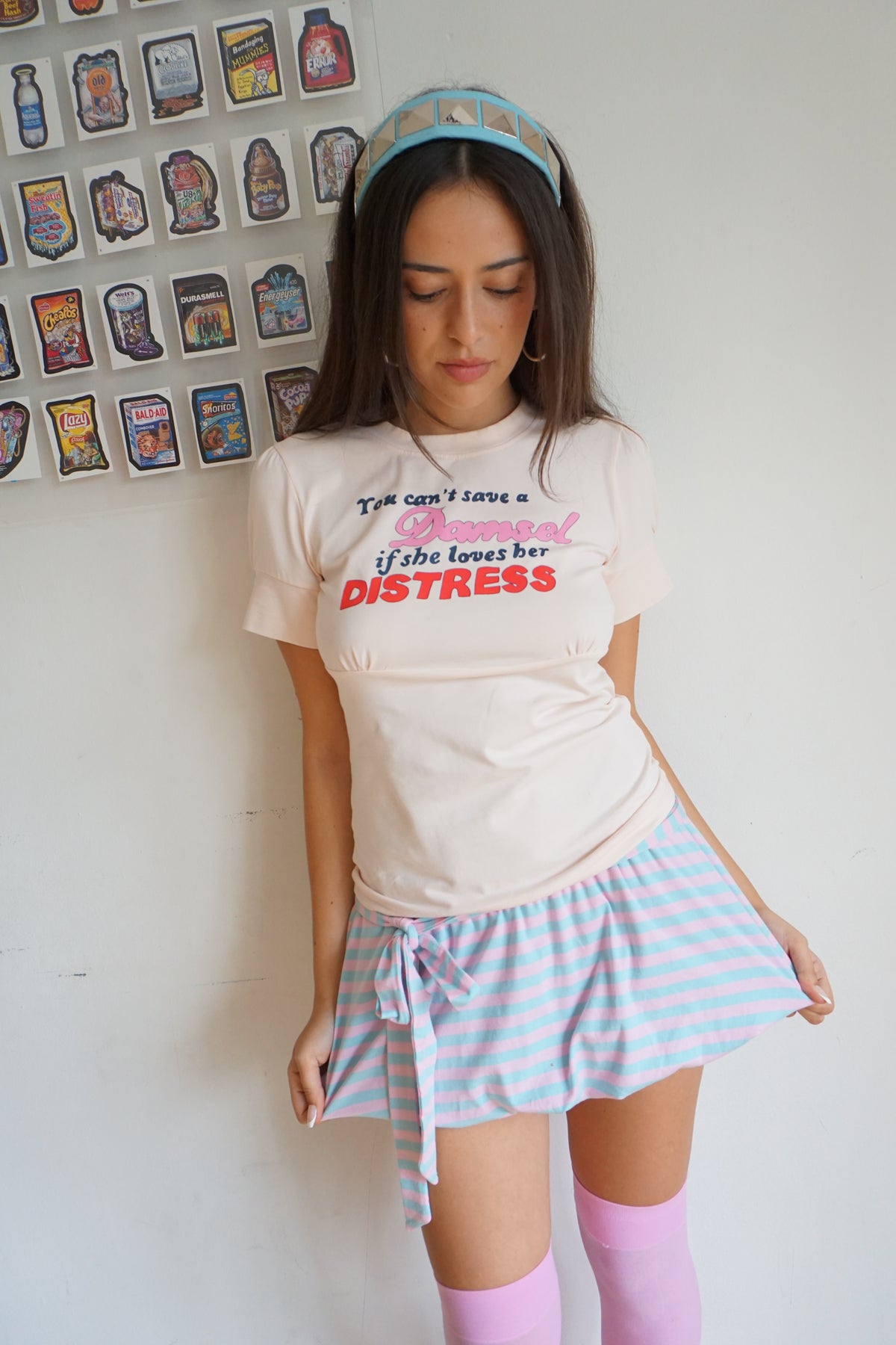 peach pink t shirt with buttons on the sleeve and a graphic that says "you can’t save a damsel if she loves her distress"