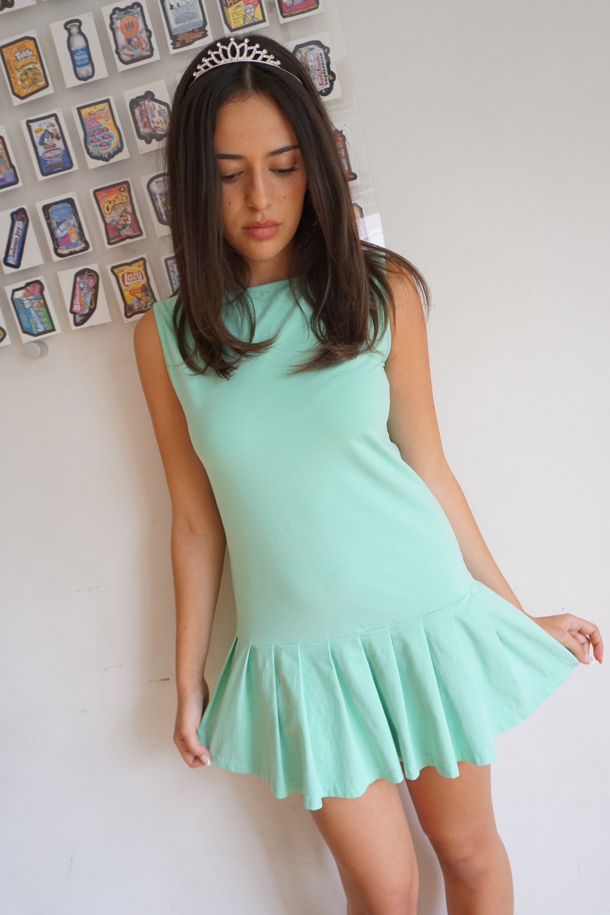 girl wearing a mint green drop waist pleated dress and a tiara