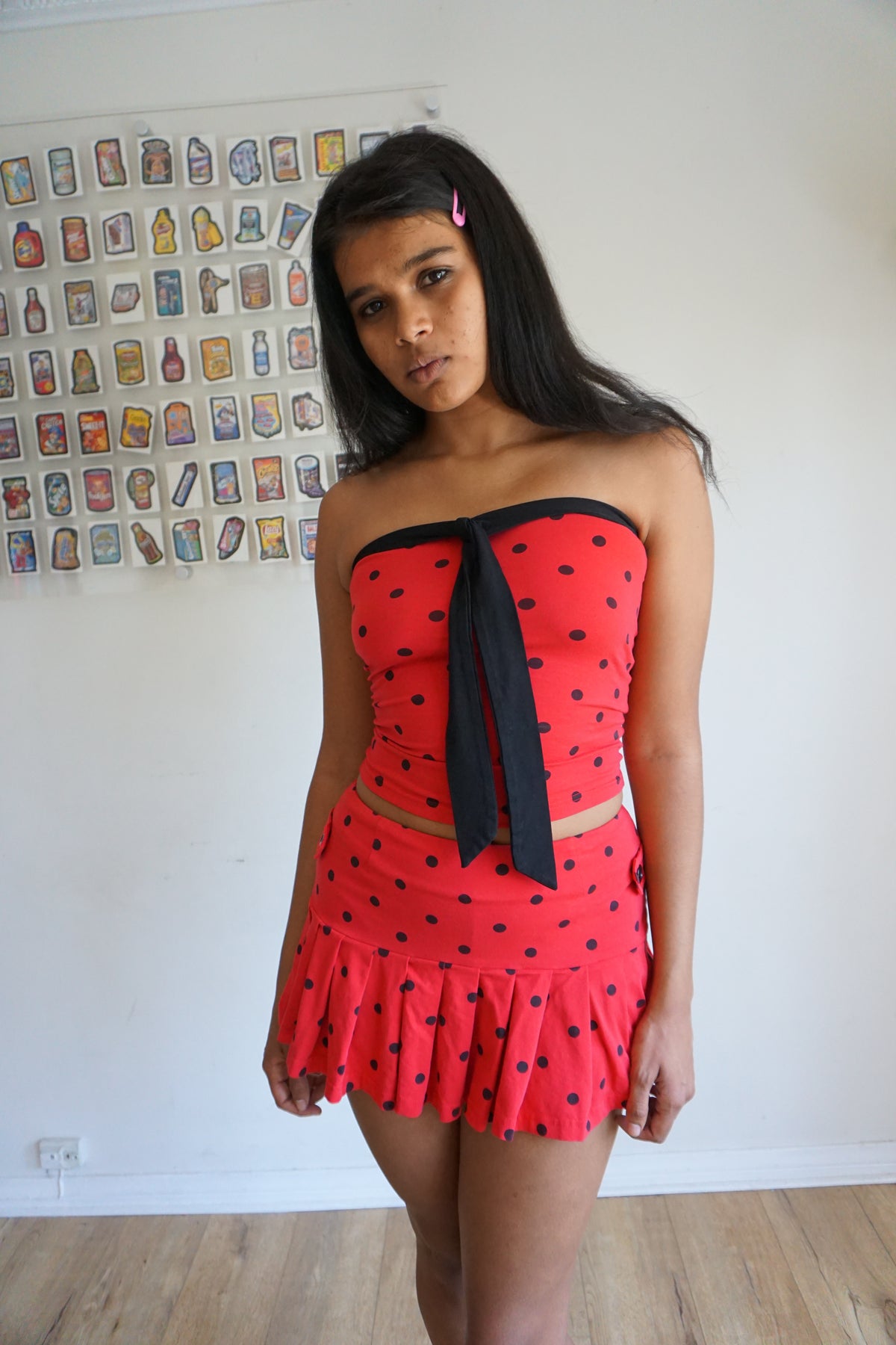 Girl wearing red tube top with black polka dots and black tie and matching skirt