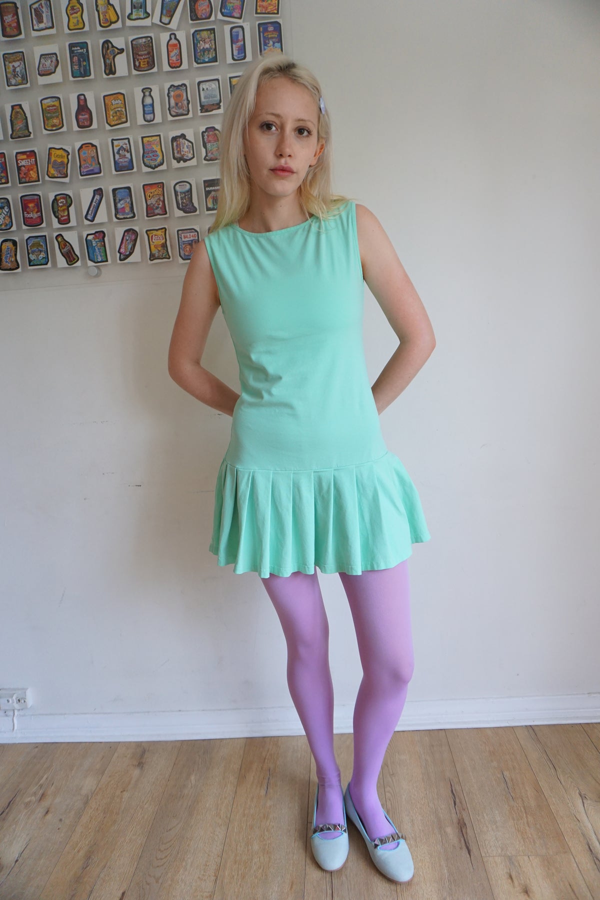 girl wearing a mint green drop waist pleated dress with purple tights 