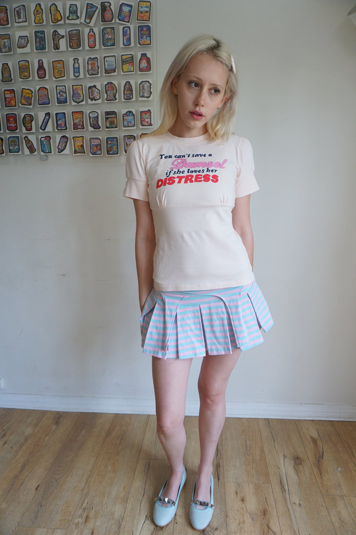 peach pink t shirt with buttons on the sleeve and a graphic that says "you can’t save a damsel if she loves her distress"