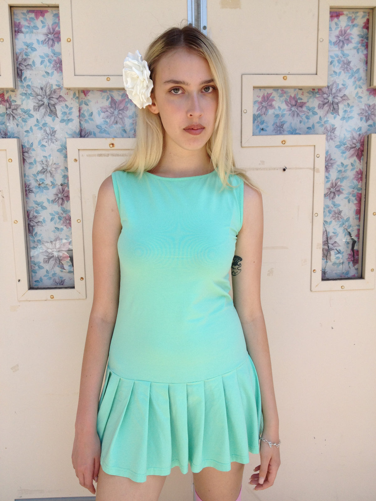 girl wearing a mint green drop waist pleated dress with flower in her hair