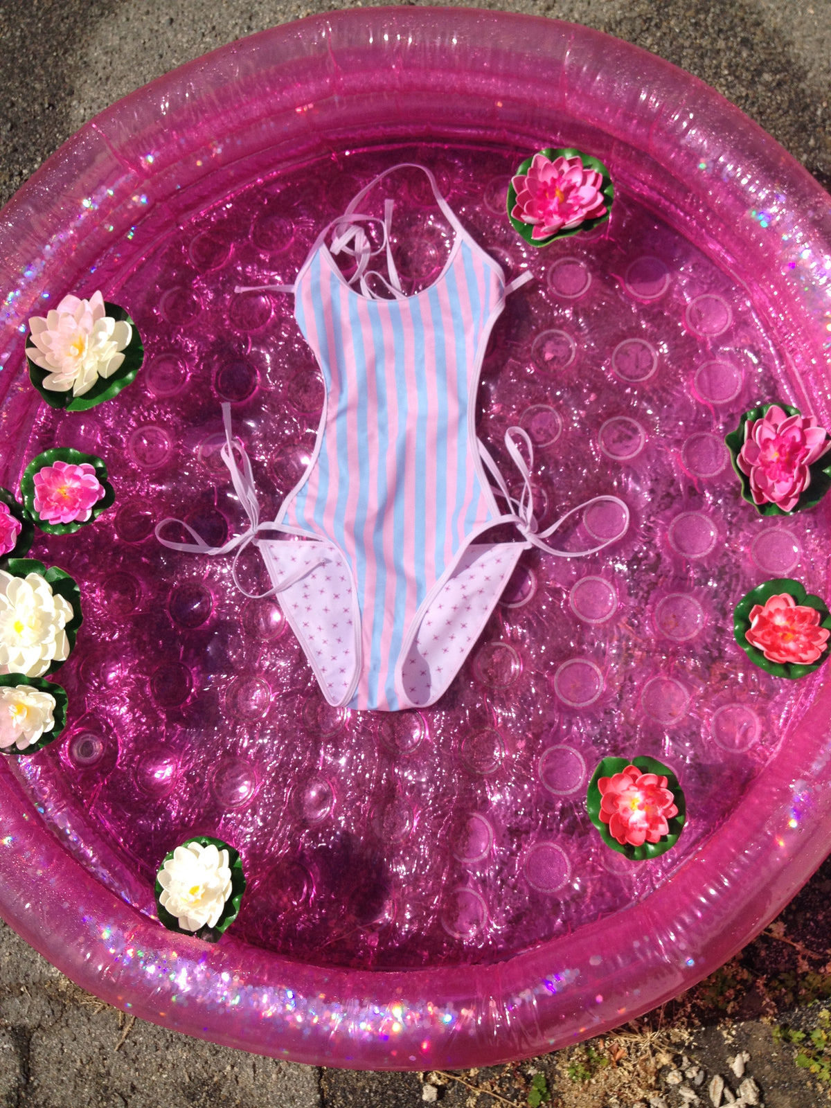 pink and blue stripe swimsuit floating in a pool with lotus flowers