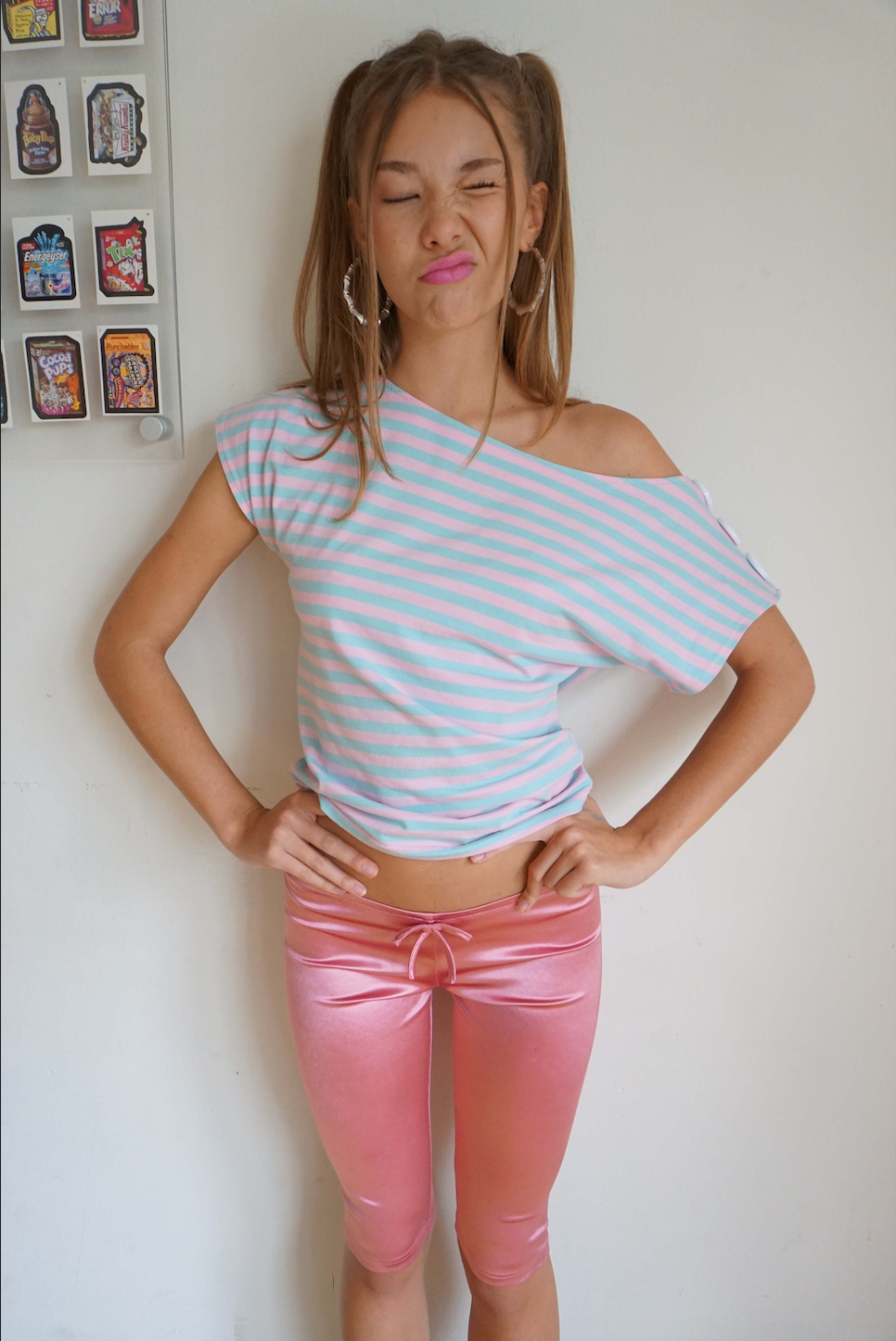 Girl wearing satin pink capris with a bow and a pink and blue stripe top 