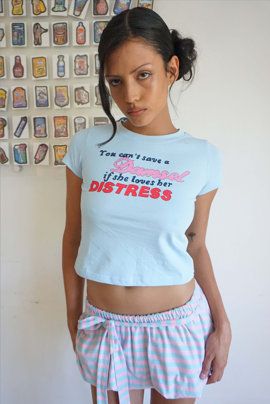 woman wearing blue baby t shirt that says you can’t save a damsel if she loves her distress